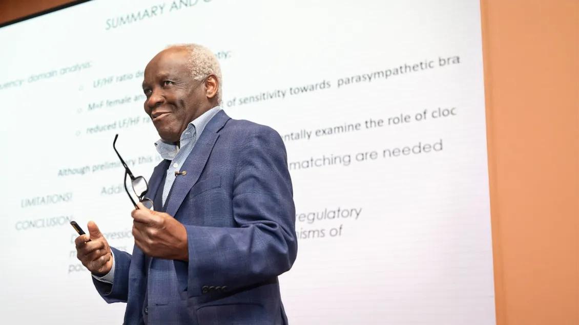 man speaking at event in front of presentation screen