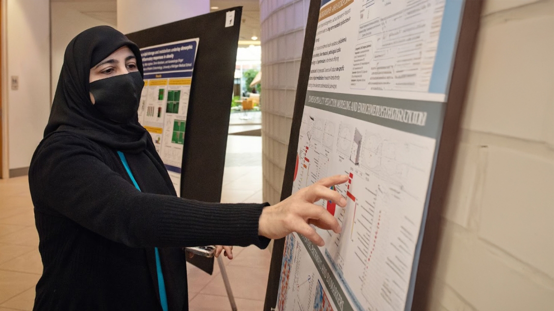 woman looking at research poster at symposium