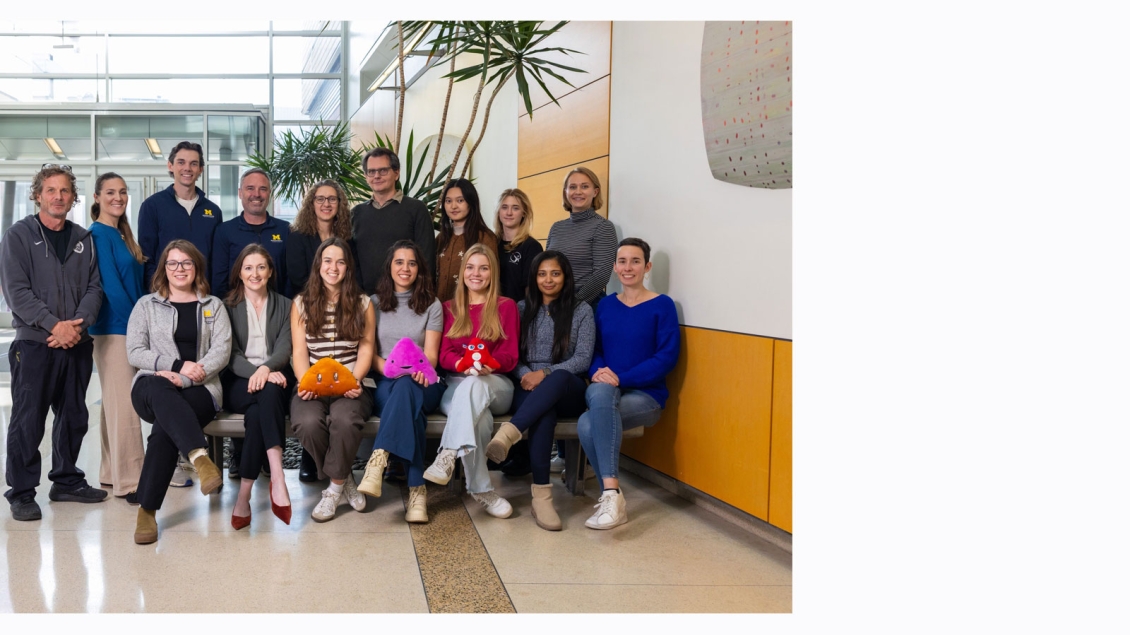 Members of the Hammer Lab - Group photo in front of a palm tree inside