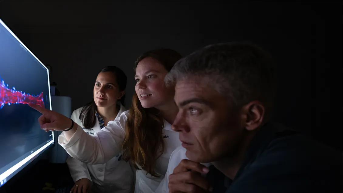 three researchers looking at a screen
