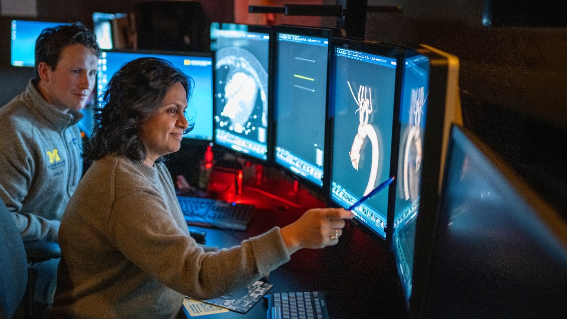 Radiology faculty pointing to a screen teaching a resident in the reading room