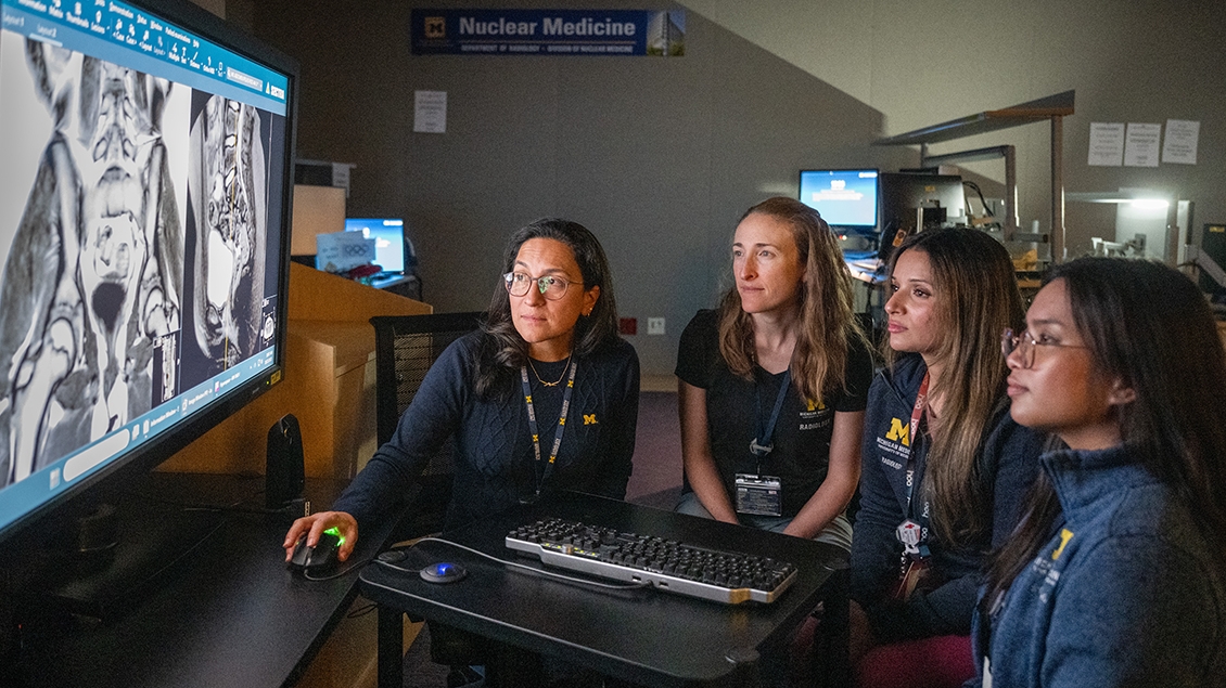 Pediatric faculty teaching a group of trainees in the reading room in front of a large monitor.