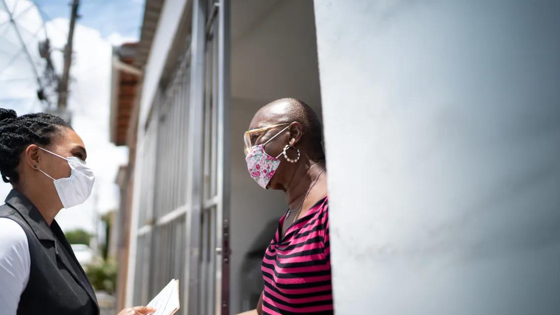 two woman talking in a doorway wearing protective masks