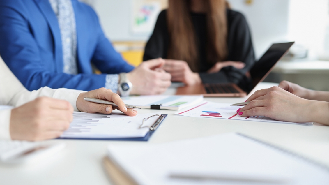 close-up of people sitting around a conference table with documents