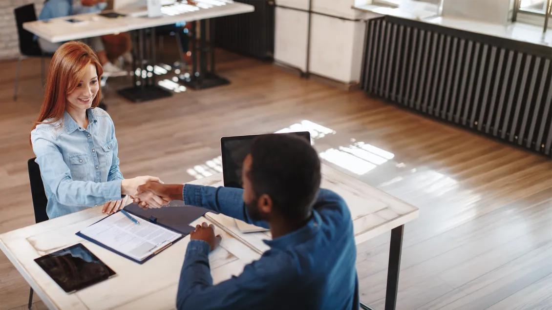 two people shaking hands at a desk