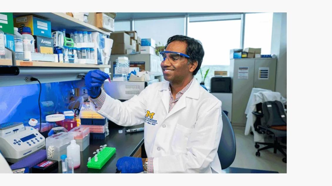 Rajesh Rao MD in his University of Michigan biomedical science lab, holding a test tube in a gloved hand