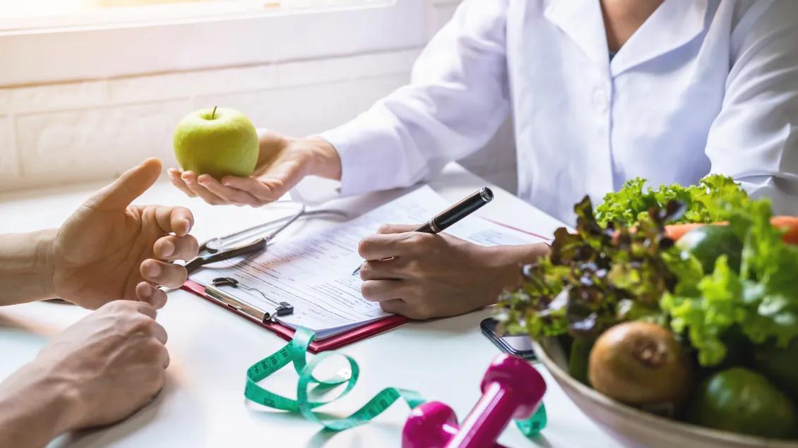 "Nutritionist giving consultation to patient with healthy fruit and vegetable