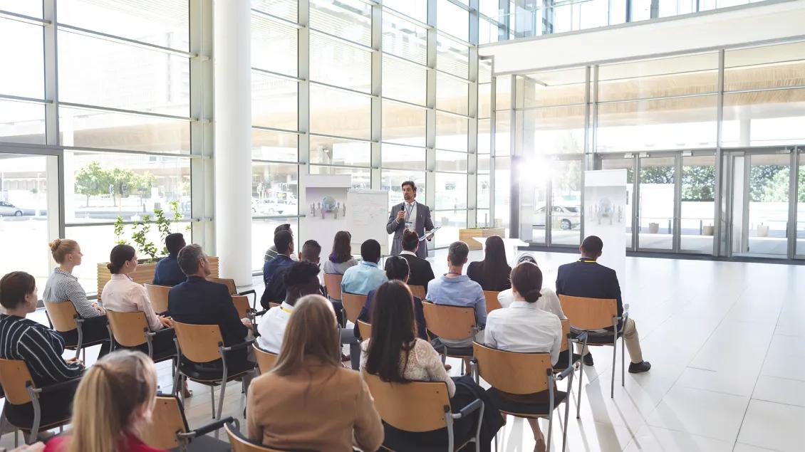 Business people listening to businessman and asking questions at conference