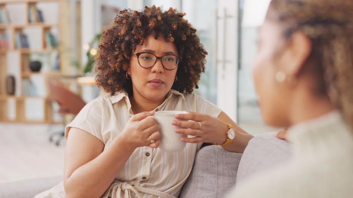 Woman holding coffee cup and talking to another woman
