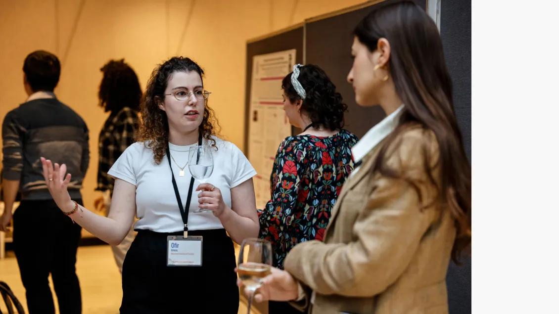 Two women researchers discuss their projects at a conference