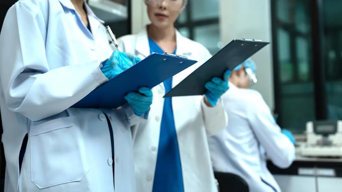 people working in a research lab holding clipboards