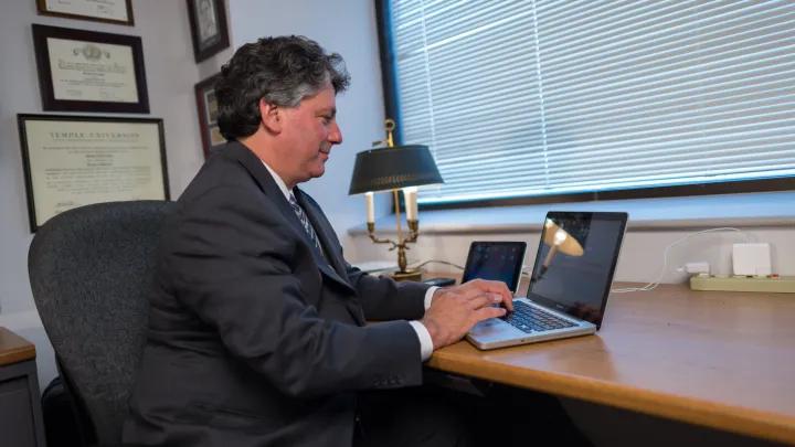 faculty member typing on computer inside office