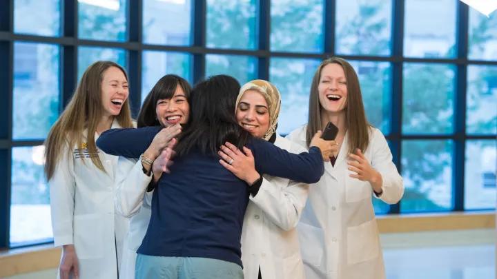 group of women hugging, all smiling.