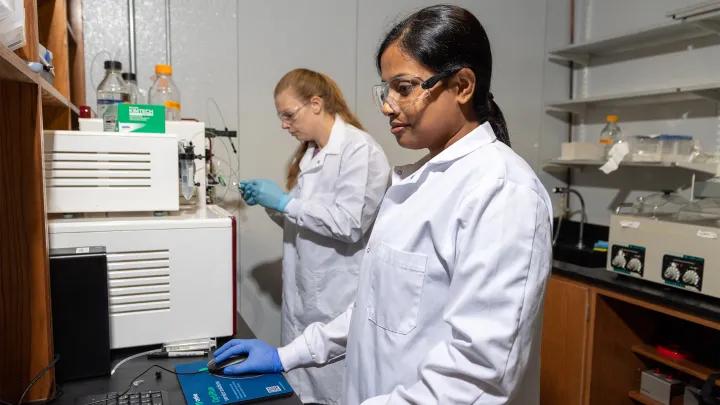 two women standing in a laboratory using a computer 
