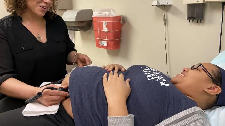 Melissa and patient Nicole lay on patient table 