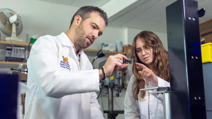 Two people in lab coats working on a project