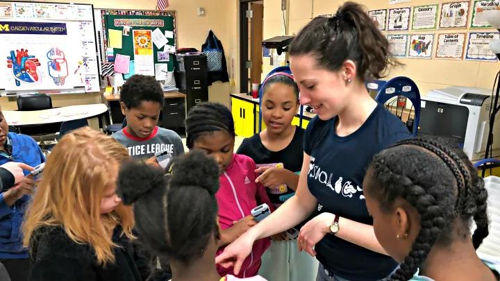 med student talking to young students in a classroom 