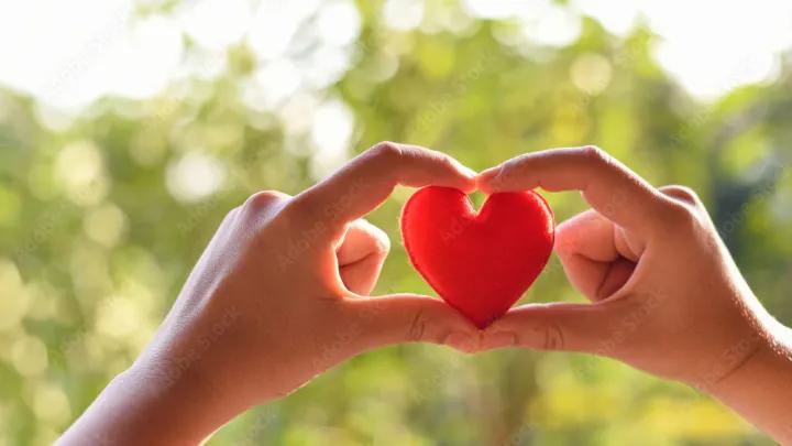Two hands holding a red heart