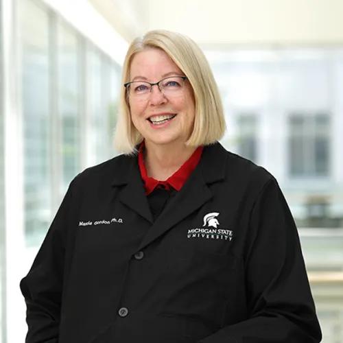 a woman with blonde hair wearing a black lab coat 
