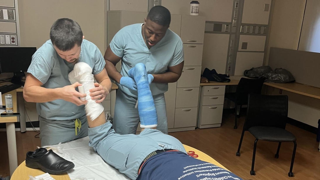 Patient lays on his stomach while doctors examine and take off casts 