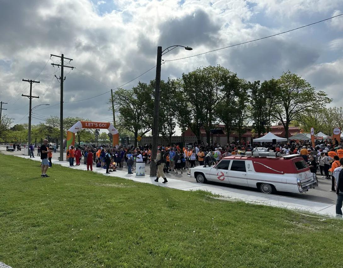 the starting line of a walk ms event with a crowd of people and a ghostbusters vehicle