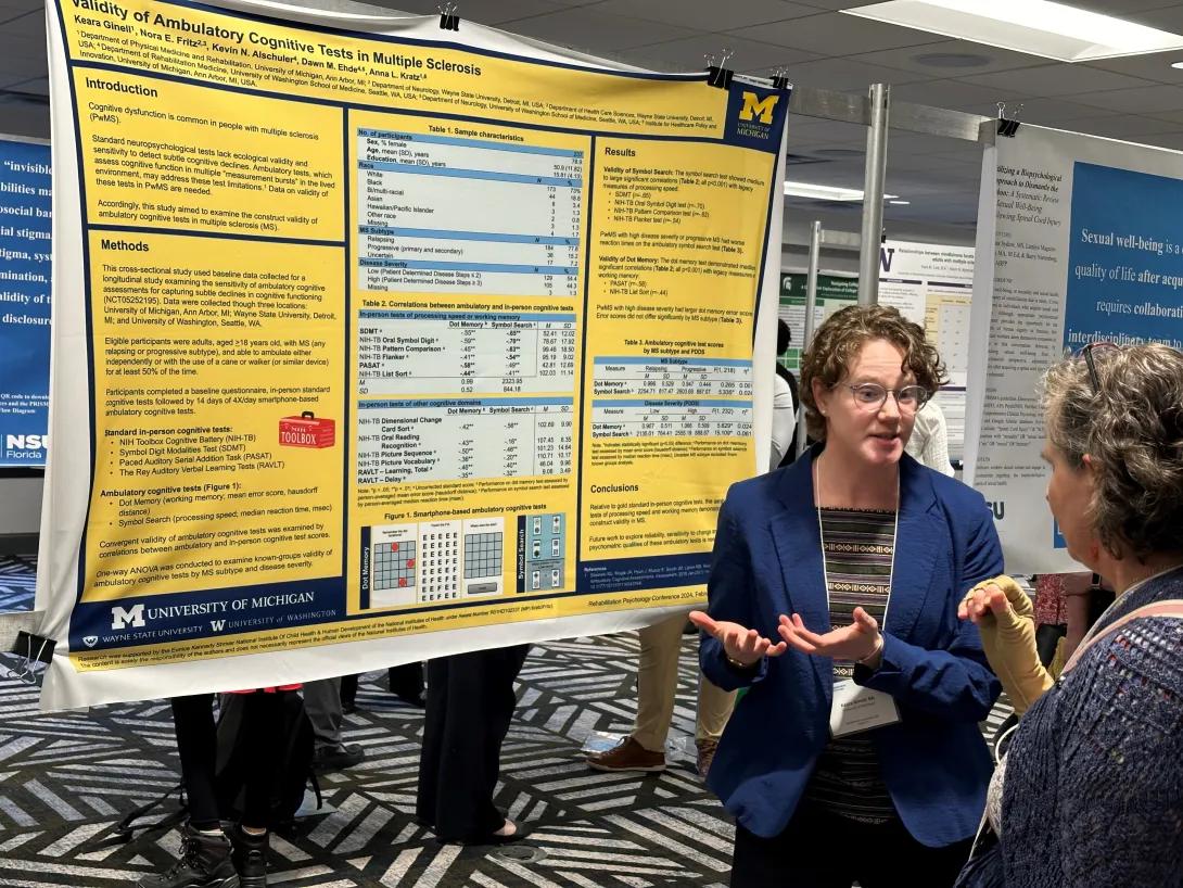 lab member discussing poster to an attendee at a conference
