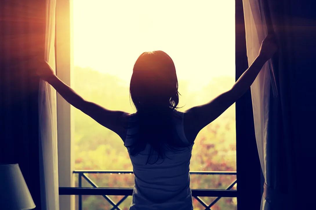 silhouette of woman standing in window at sunrise