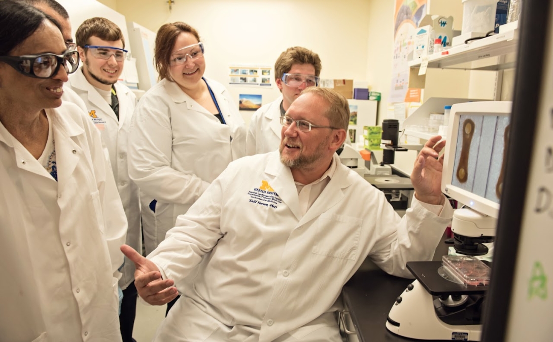A group of researcher smiling and working in a lab.