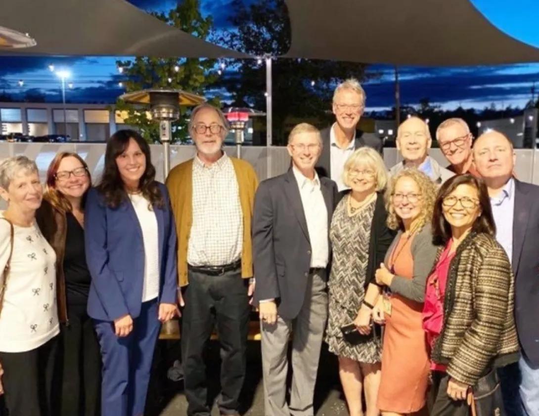 A group of colleagues posing together outdoors during an evening gathering.