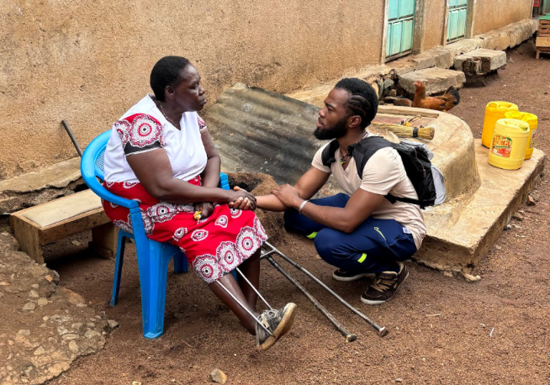 Dr. Mwenesi talking to a patient sitting with an injured leg
