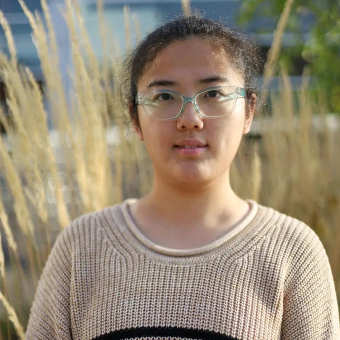 a woman with glasses and a beige sweater 