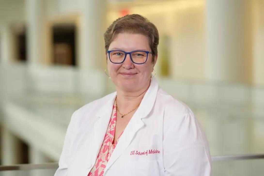 a woman with blonde hair wearing a white coat and pink shirt 