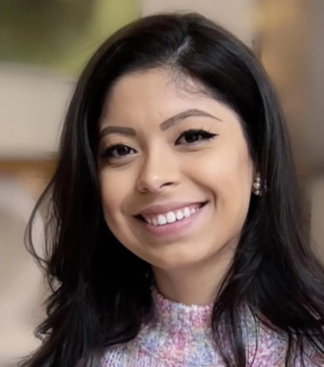 a woman with dark hair in a pink sweater 