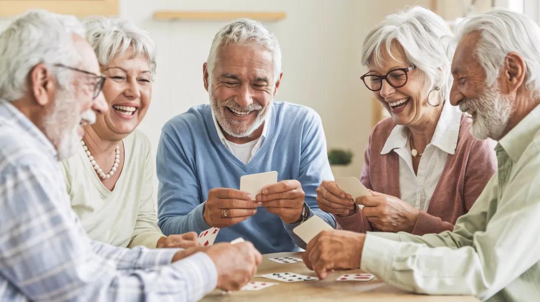 a group of older people playing cards and smiling