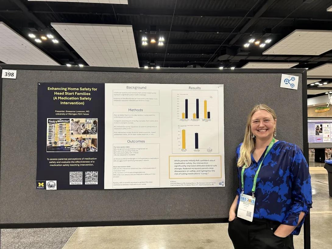 a PAS attendee poses in front of poster
