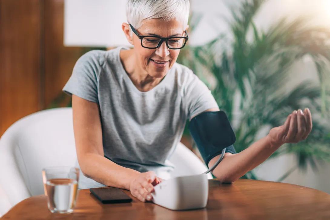 an older women with glasses and short hair taking her blood pressure