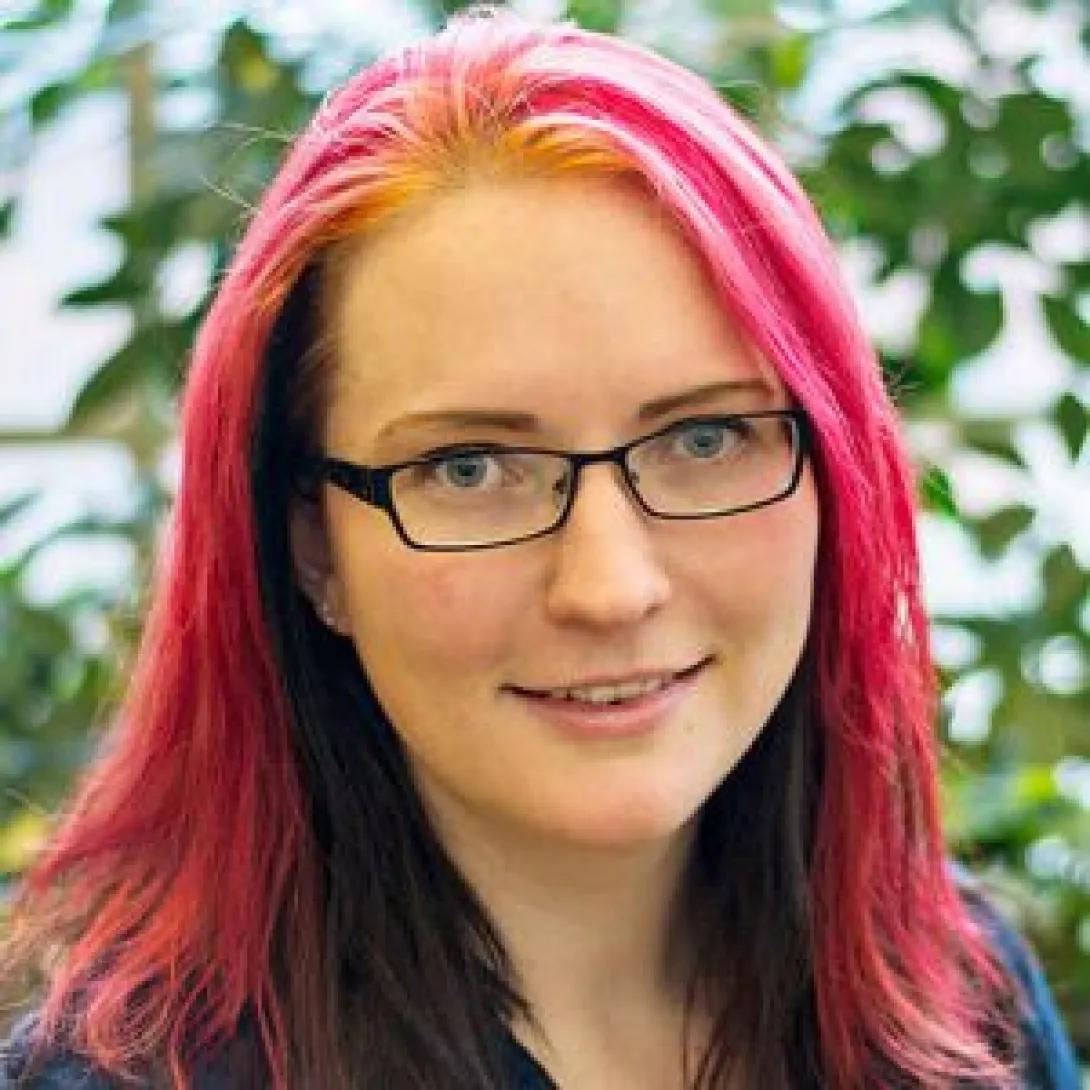 a woman with pink hair and glasses 