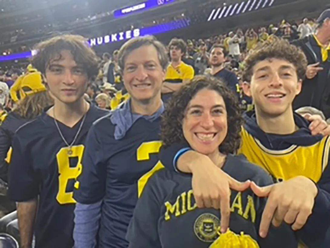 Smiling photo of the Saiontz family wearing U-M gear at a football game.