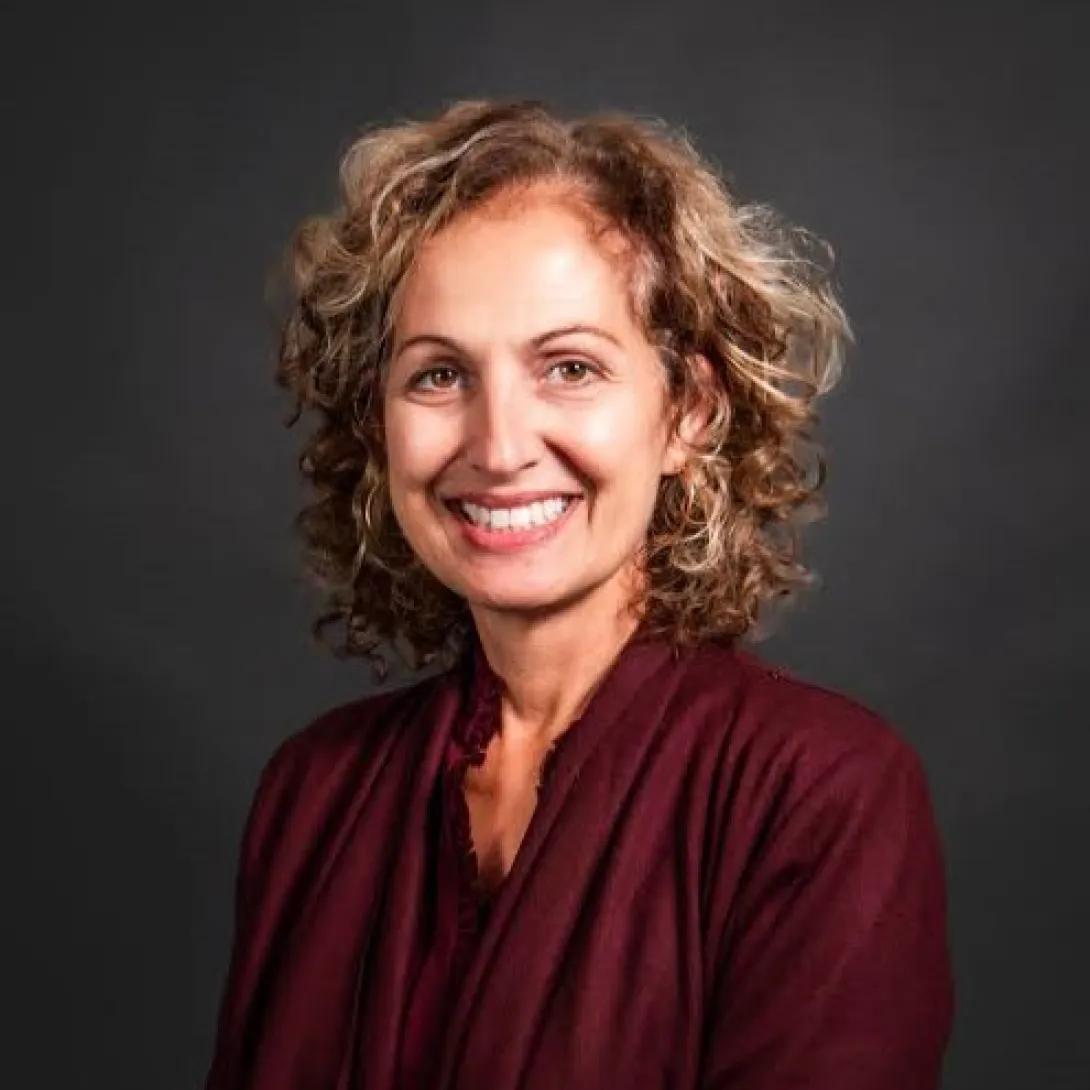 a woman with curly hair and a burgundy blouse 