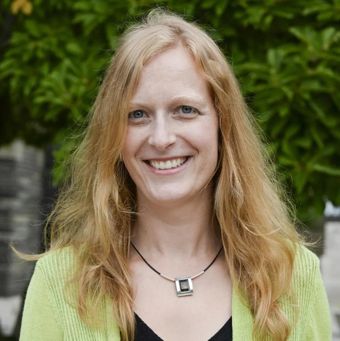 a woman smiling with blonde hair and a green sweater