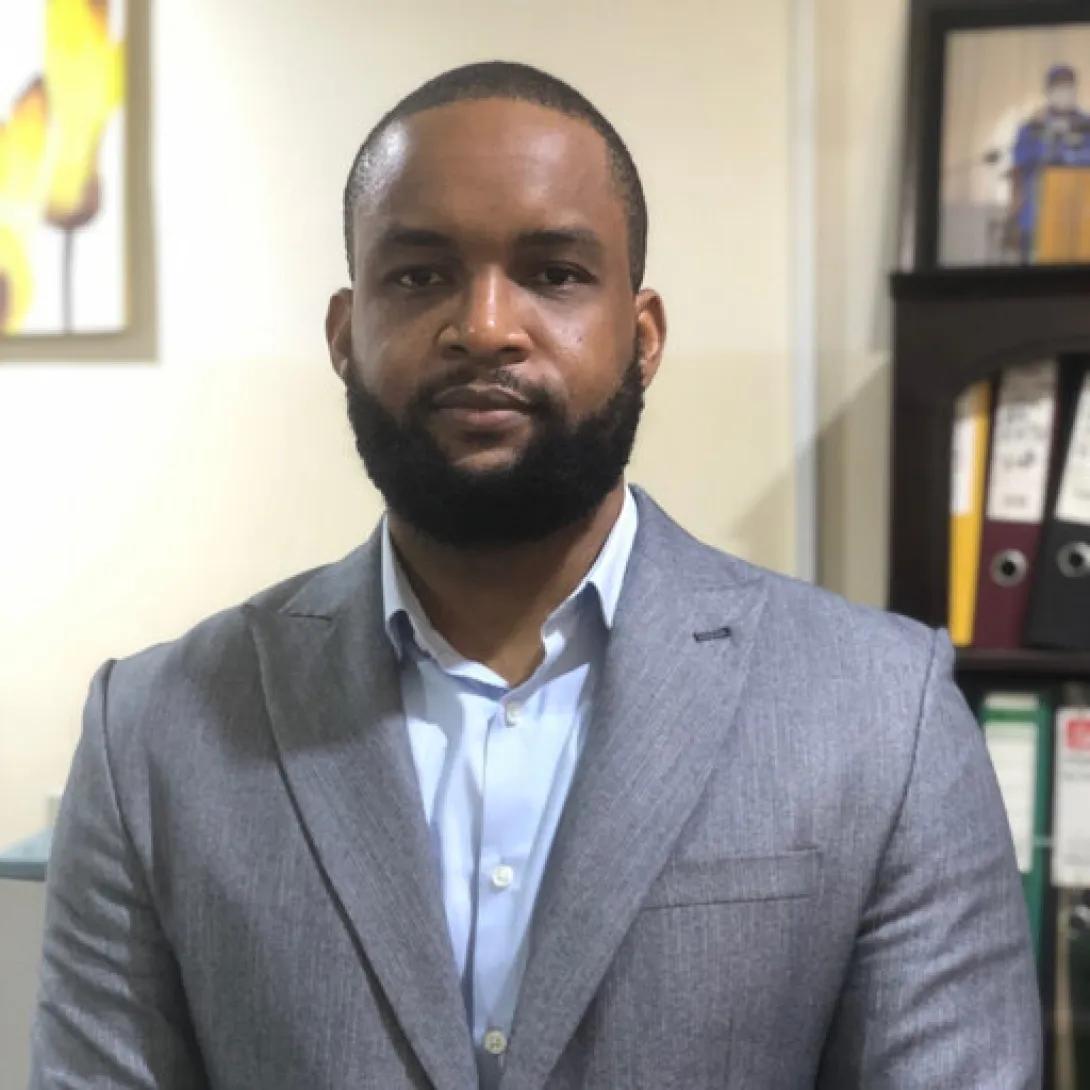 a Black man wearing a grey suit with a beard
