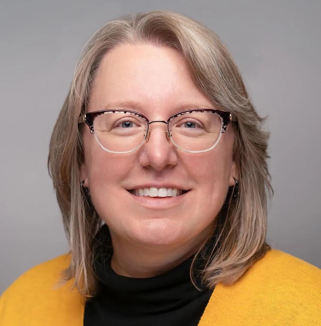 a woman with light blonde hair and a yellow sweater