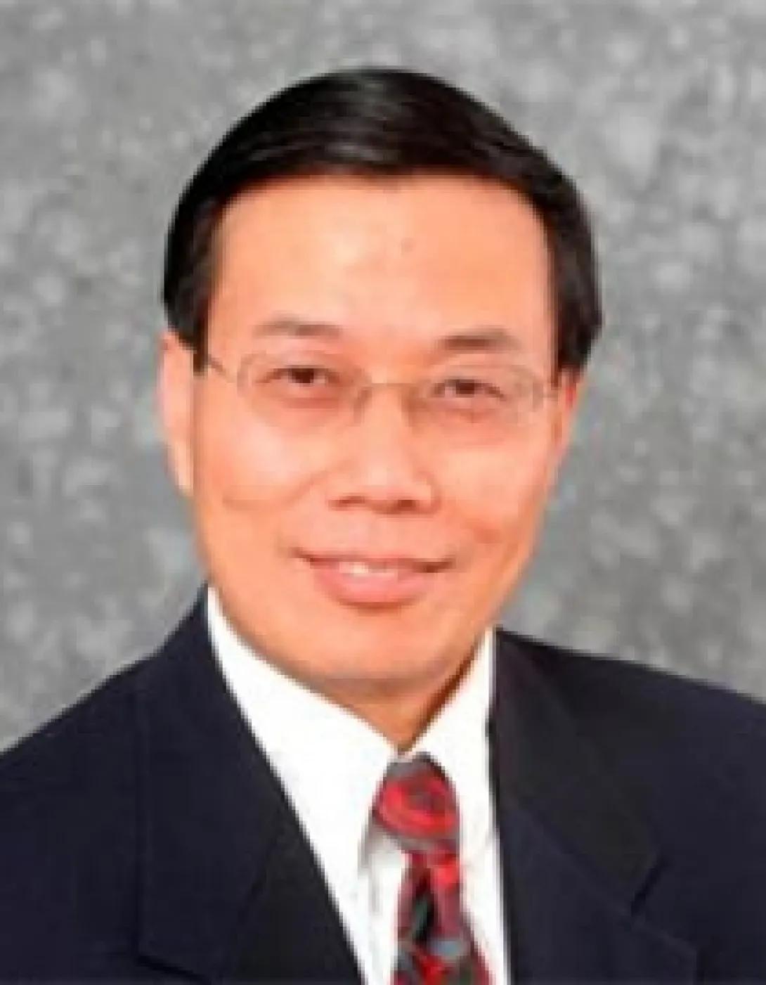 a middle aged Asian man with dark brown hair and glasses wearing a suit with a red tie 