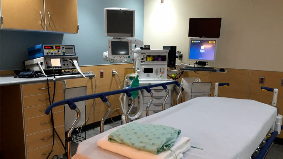 Hospital bed with hospital gown and towel folded at the edge.