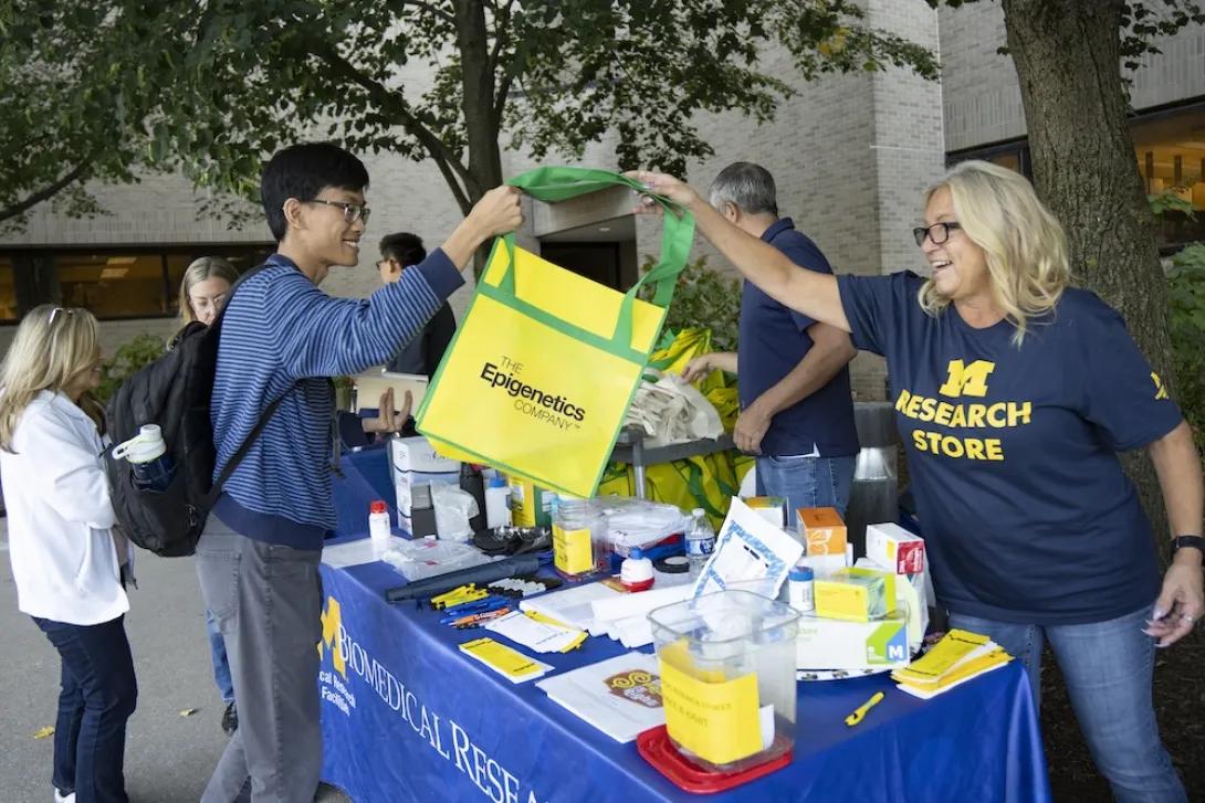 Photo of two people at a table handing over a free bag