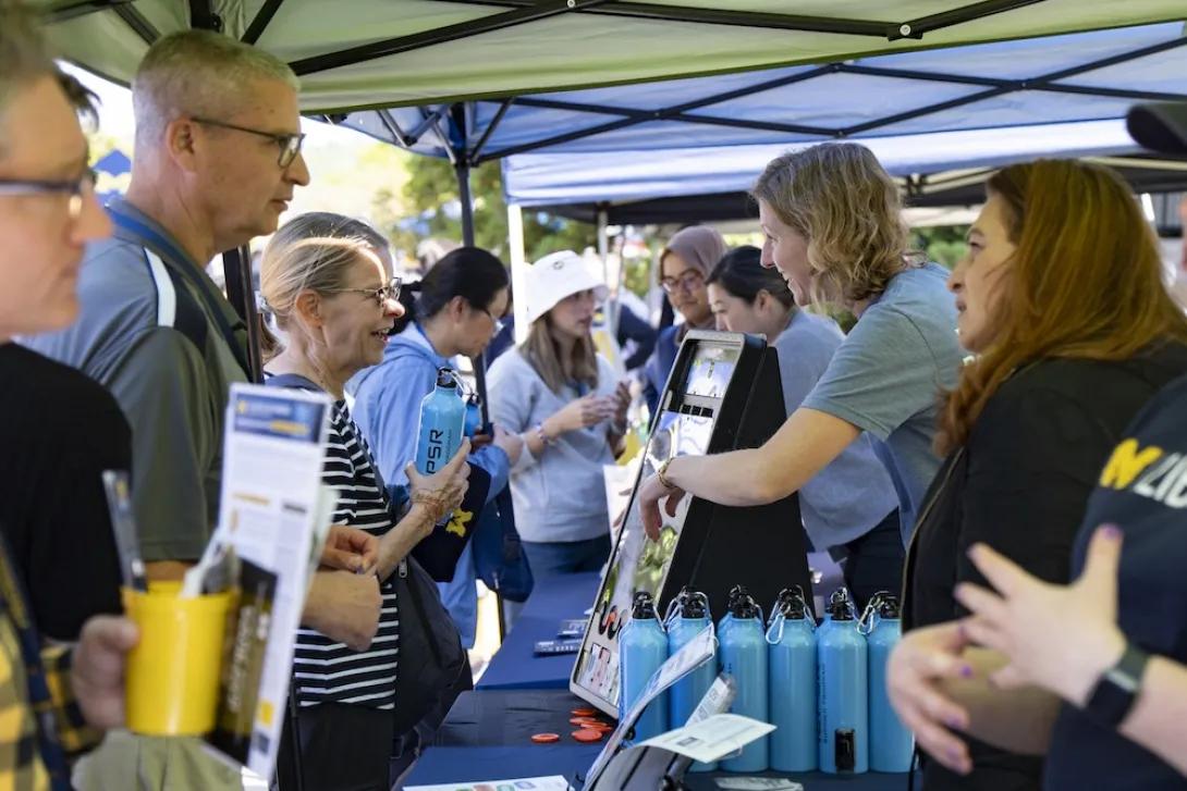 Photo of Researchpalooza attendees and staff talking at a booth