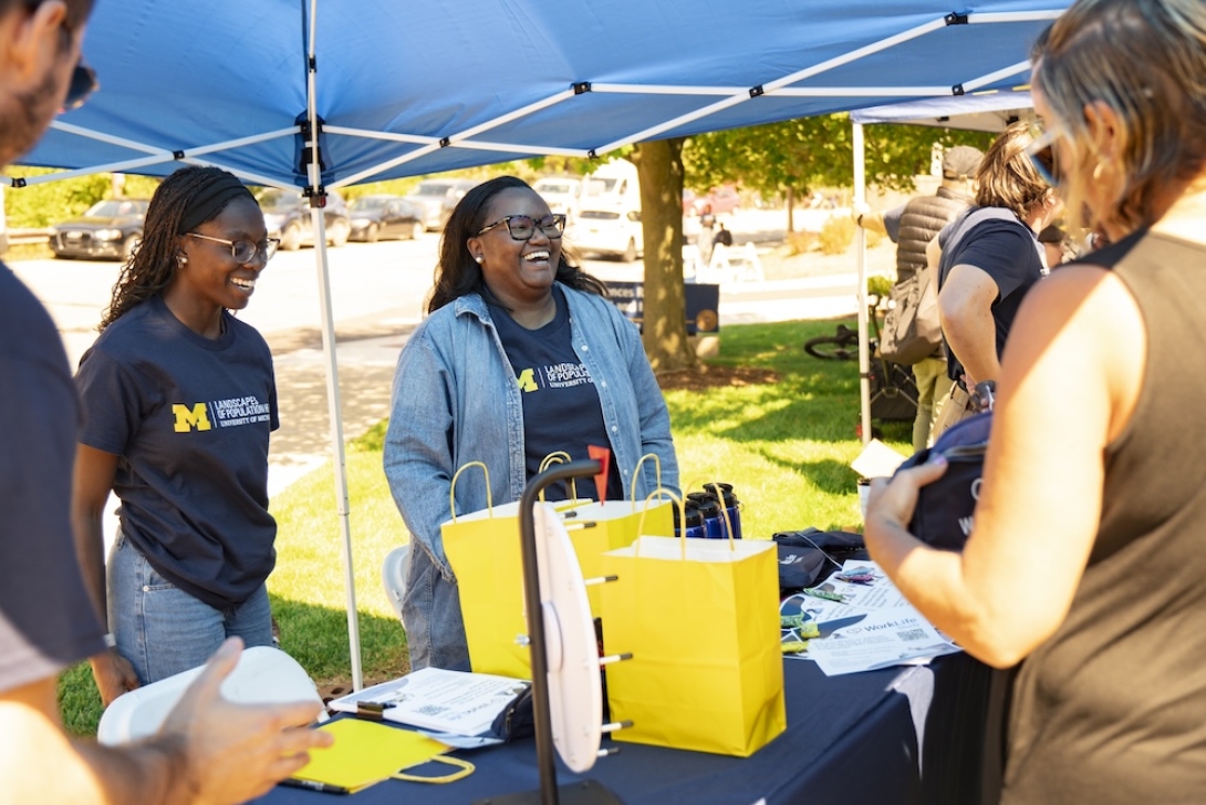 Photo of staff smiling and laughing while talking to Researchpalooza attendee
