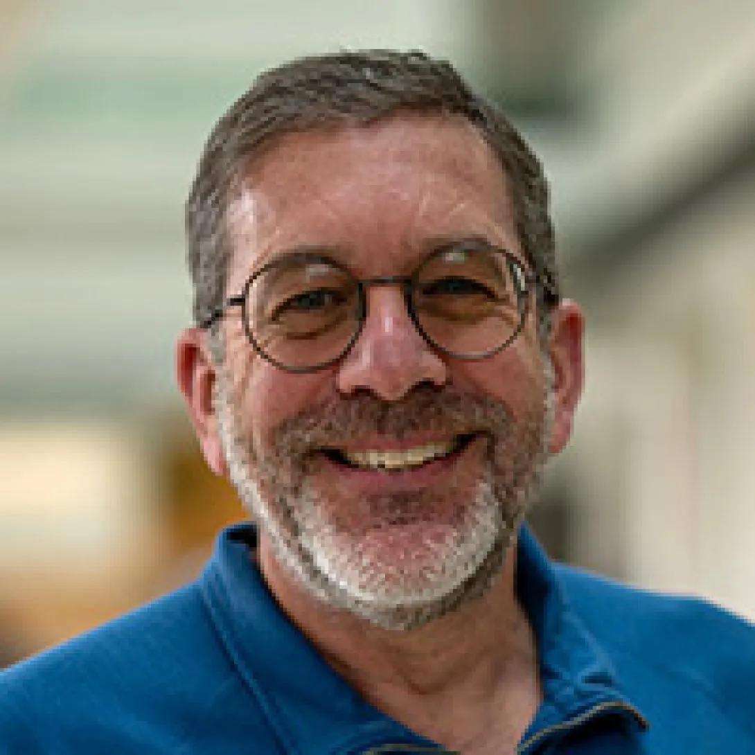 a man with a blue shirt and circle glasses