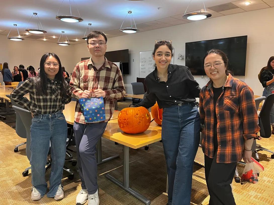 group of people posing for the camera with pumpkins