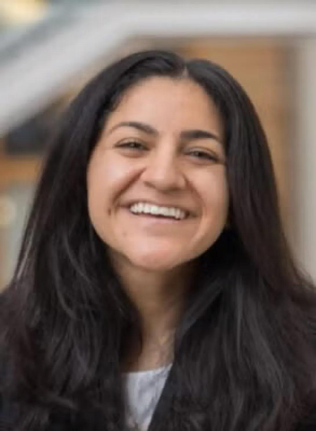 Headshot of woman smiling with long dark hair and black blazer
